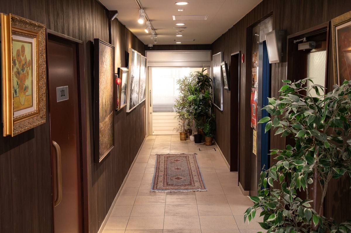 Corridor with framed paintings, a rug and potted plants